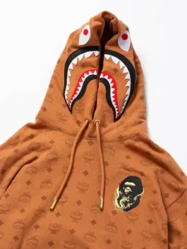 MCM x BAPE Monogram Shark Hoodie in rich brown fleece with bold shark monogram design and a clean hooded pullover everyday luxury streetwear build.