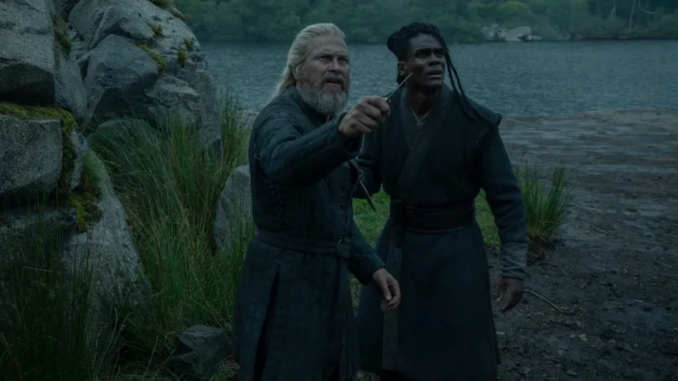 Corlys Velaryon Steve Toussaint and Addam of Hull Clinton Liberty in House of the Dragon Season 3 standing by lake in dark robes outdoor scene