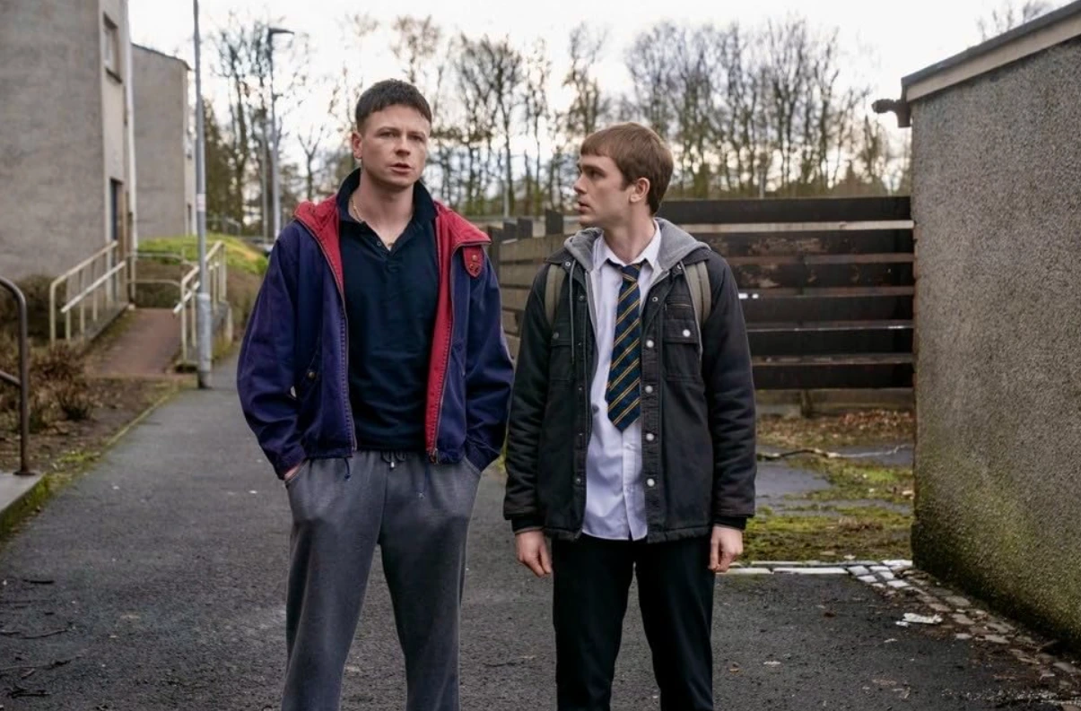 Stuart Campbell as young Ruben in a navy and red track jacket and Mitchell Robertson as young Niall in a dark jacket and school uniform in Half Man 2026