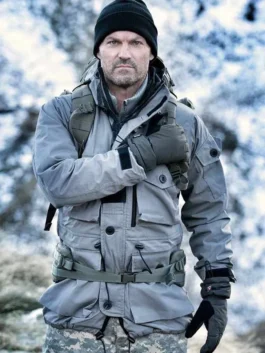 Front view of Brian Austin Green wearing a grey tactical parka jacket with multi-pocket utility design and black beanie in snowy outdoor setting.