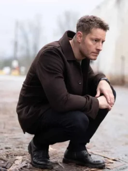 Justin Hartley as Colter Shaw in Tracker S03 crouching outdoors in a dark brown wool jacket.