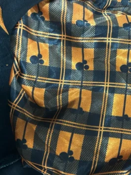 Close-up of the smooth inner lining of the Disney Mickey Mouse & Friends Halloween denim jacket, featuring a black and orange plaid pattern accented with small Mickey Mouse head shapes.