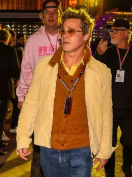 Brad Pitt walking outdoors at night wearing a light pastel yellow cotton casual jacket layered over a brown sweater vest with aviator sunglasses.