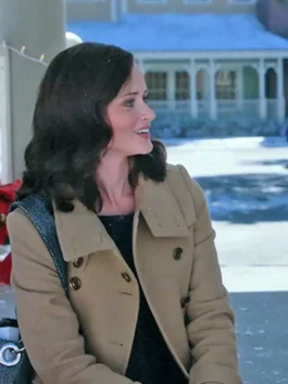 Upper body shot of Rory Gilmore wearing a light brown tailored wool coat with wide lapels and dark contrast buttons.
