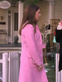 Side profile view of Lorelai Gilmore walking outside Kim's Antiques wearing a tailored pink wool trench coat.