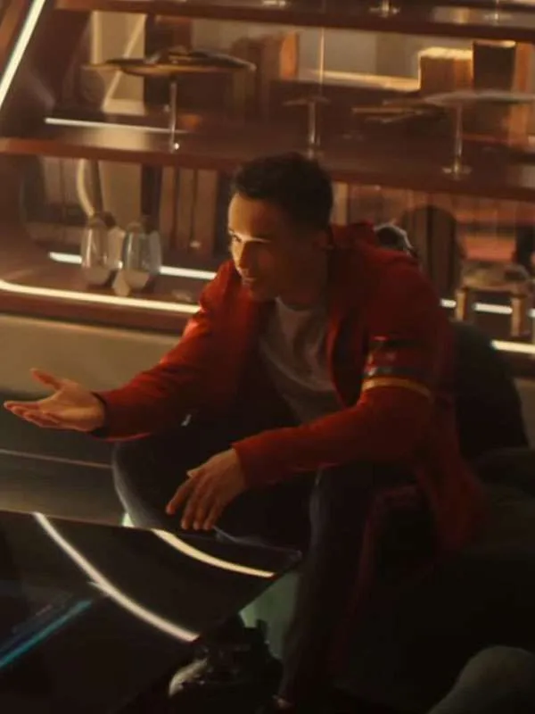 A Klingon character smiling while wearing a bright red Starfleet Academy zip-up hoodie with black, red, and gold stripes on the left sleeve.