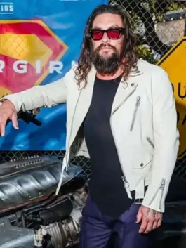 Jason Momoa wearing an off-white asymmetrical biker leather jacket with red tinted sunglasses at the Supergirl event posing by a motorcycle