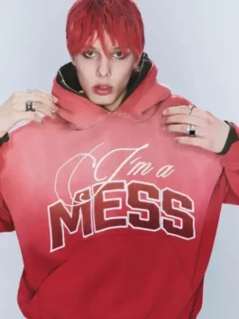Landon Barker with bright red hair wearing the faded red "I'm a MESS" ombre hoodie while posing with hands near the collar.
