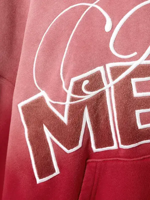 Extreme close-up of the textured towel-style chenille embroidery on the "MESS" block letters of the red hoodie.
