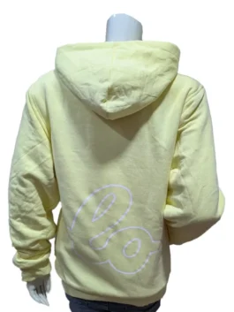 Rear view of the pastel yellow Lola Winters hoodie on a mannequin, showing the comfortable draped hood and a large white cursive outline graphic printed across the lower back panel.