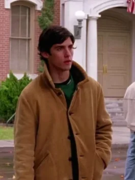 Milo Ventimiglia as Jess Mariano in Gilmore Girls wearing a tan brown suede coat with a stand-up collar and front button closure.