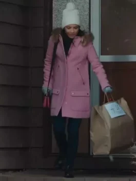 Full-length view of Jackie Howard walking outdoors in a long pink parka coat with fur trim, white beanie, and dark trousers.