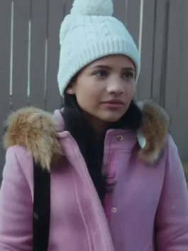 Close-up of Nikki Rodriguez as Jackie Howard wearing a pink parka coat with a fur hood and a white knit beanie.