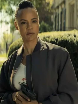 Close-up of Maria Sten as Frances Neagley wearing a dark grey bomber jacket with a rib-knit stand collar and zipper closure over a white printed t-shirt.