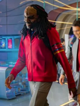 Karim Diane as a cadet in Star Trek: Starfleet Academy, wearing a casual red zip-up hoodie with multi-colored rank stripes on the sleeve while seated in a futuristic lounge.