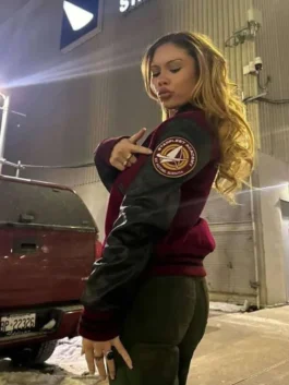 A woman posing from the side to show off the maroon Starfleet Academy varsity bomber jacket with black leather sleeves and a round sleeve patch.