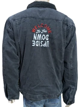 Rear view of the washed black Stranger Things denim jacket on a mannequin, showcasing the black sherpa collar and embroidered "Welcome to the Upside Down" text across the back.