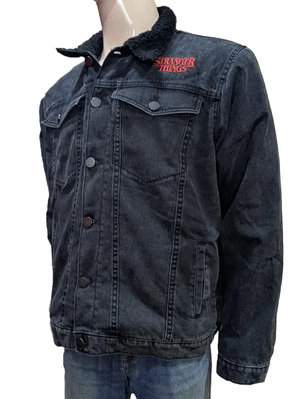 Front three-quarter view of the Stranger Things black denim jacket on a mannequin, highlighting the red embroidered logo on the chest and the textured black sherpa collar.