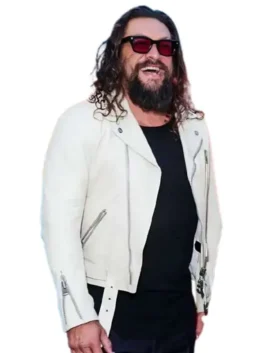 Jason Momoa smiling in an off-white asymmetrical leather biker jacket with silver zipper accents and waist belt