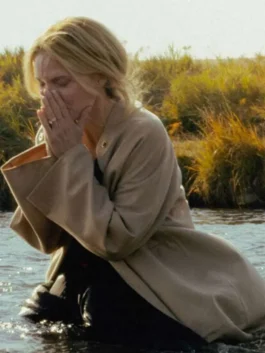 Medium shot of Michelle Pfeiffer kneeling in water wearing a loose-fit beige wool coat in a dramatic scene from The Madison.