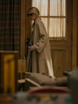 Side view of Michelle Pfeiffer wearing a beige wool coat and sunglasses while stepping through a doorway in The Madison.