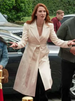 Monica Stevens walking outdoors in a long off-white leather trench coat tied at the waist with peak lapels