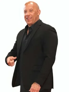 Vin Diesel smiling and pointing forward while wearing a tailored black single-breasted blazer over a matching black button-down shirt.